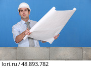 Engineer unrolling blurpints. Стоковое фото, агентство Ingram Publishing / Фотобанк Лори