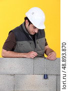 A mason using a plumb bob to check his wall. Стоковое фото, агентство Ingram Publishing / Фотобанк Лори