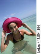 beaming young woman bathing with hands to her sun hat. Стоковое фото, агентство Ingram Publishing / Фотобанк Лори