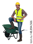 Man casually stood by empty wheelbarrow. Стоковое фото, агентство Ingram Publishing / Фотобанк Лори
