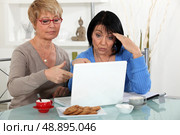 Older women puzzling over a laptop. Стоковое фото, агентство Ingram Publishing / Фотобанк Лори