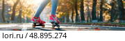 A woman rollerblades down a paved path in an autumn park. The sunlight shines through the trees, casting warm hues across the scene. Стоковое AI-изображение, AI-художник Данила Большаков / Фотобанк Лори