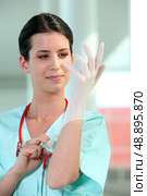 female doctor putting on rubber gloves. Стоковое фото, агентство Ingram Publishing / Фотобанк Лори