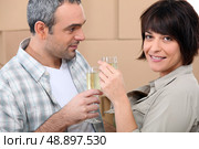 Couple drinking champagne in front of a pile of cardboard boxes. Стоковое фото, агентство Ingram Publishing / Фотобанк Лори
