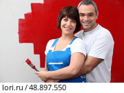 couple painting a wall in red. Стоковое фото, агентство Ingram Publishing / Фотобанк Лори