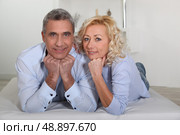 Man and woman lying with their heads propped up on their hands. Стоковое фото, агентство Ingram Publishing / Фотобанк Лори