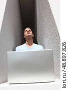 Man in an alcove basking in the sunshine whilst using a laptop. Стоковое фото, агентство Ingram Publishing / Фотобанк Лори