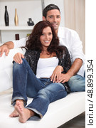 Young couple sat on couch at home. Стоковое фото, агентство Ingram Publishing / Фотобанк Лори