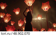 A woman stands confidently in front of numerous red lanterns hanging above her, creating a vibrant and cultural backdrop. Стоковое AI-изображение, AI-художник Данила Большаков / Фотобанк Лори