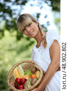 blonde woman showing a fruits basket. Стоковое фото, агентство Ingram Publishing / Фотобанк Лори