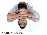 Woman with her eyes closed leaning on a mirrored table. Стоковое фото, агентство Ingram Publishing / Фотобанк Лори