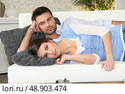 Couple lying on a couch together. Стоковое фото, агентство Ingram Publishing / Фотобанк Лори