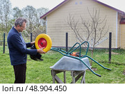 Unpacking new wheel and preparing for replacement of damaged tire on garden wheelbarrow to ensure smooth transport of heavy loads. Стоковое фото, фотограф Владимир Григорьев / Фотобанк Лори