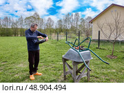 Removing packaging from new tire and getting ready to install wheel on garden wheelbarrow for maintenance and improved functionality outdoors. Стоковое фото, фотограф Владимир Григорьев / Фотобанк Лори