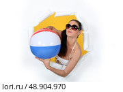 Woman with beach ball coming out of hole. Стоковое фото, агентство Ingram Publishing / Фотобанк Лори
