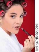 Woman wearing rollers and applying lip gloss. Стоковое фото, агентство Ingram Publishing / Фотобанк Лори
