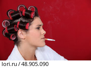 woman with hair curlers against red background smoking. Стоковое фото, агентство Ingram Publishing / Фотобанк Лори