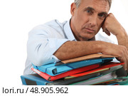 Man leaning on stack of work. Стоковое фото, агентство Ingram Publishing / Фотобанк Лори