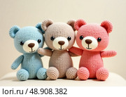 Three adorable knitted teddy bears in pastel blue, brown, and pink are joyfully displayed together in a soft, cozy ambiance. Each bear showcases unique craftsmanship, inviting warmth Generative AI. Стоковое AI-изображение, AI-художник Юлия Петровская / Фотобанк Лори