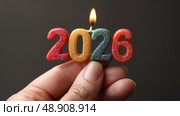 Горящие свечи с цифрами 2026. Блестящие разноцветные свечи, образующие цифру 2026, с единственным пламенем наверху, зажатые между пальцами на нейтральном фоне. Стоковое AI-изображение, AI-художник Анна Чижова / Фотобанк Лори