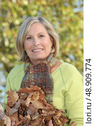 Woman with an armful of autumnal leaves. Стоковое фото, агентство Ingram Publishing / Фотобанк Лори