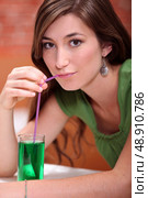 young woman dressed in green drinking a lemonade and mint cordial with a drinking straw. Стоковое фото, агентство Ingram Publishing / Фотобанк Лори