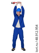 craftsman holding up adjustable spanner. Стоковое фото, агентство Ingram Publishing / Фотобанк Лори