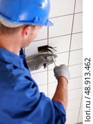 Electrician screwing plug. Стоковое фото, агентство Ingram Publishing / Фотобанк Лори