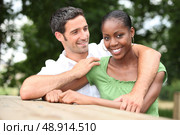 Mixed race couple cuddling in the countryside. Стоковое фото, агентство Ingram Publishing / Фотобанк Лори