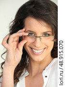 Brunette touching glasses fame. Стоковое фото, агентство Ingram Publishing / Фотобанк Лори