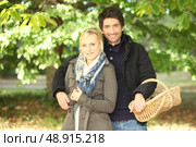 young couple behind trees in autumn, man holding a wickerwork basket. Стоковое фото, агентство Ingram Publishing / Фотобанк Лори