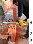 Man using a chainsaw to cut through a brick. Стоковое фото, агентство Ingram Publishing / Фотобанк Лори