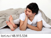 Man looking at his partner’s feet in bed. Стоковое фото, агентство Ingram Publishing / Фотобанк Лори