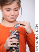 Young girl putting used batteries in a plastic container. Стоковое фото, агентство Ingram Publishing / Фотобанк Лори