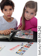 Two young children stamp collecting. Стоковое фото, агентство Ingram Publishing / Фотобанк Лори
