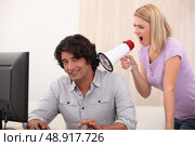 a man doing computer and a woman yelling on him with a megaphone. Стоковое фото, агентство Ingram Publishing / Фотобанк Лори