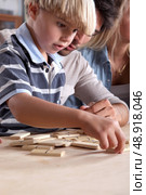 Young boy playing dominoes with his father. Стоковое фото, агентство Ingram Publishing / Фотобанк Лори