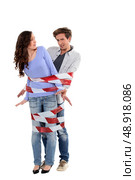 Couple being forcibly held together by caution tape. Стоковое фото, агентство Ingram Publishing / Фотобанк Лори