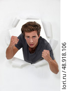 Young man punching his way through a barrier. Стоковое фото, агентство Ingram Publishing / Фотобанк Лори
