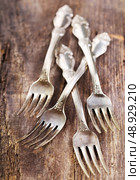 Vintage silverware forks lying on rustic wooden table. Стоковое фото, агентство Ingram Publishing / Фотобанк Лори