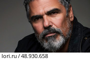 A close-up portrait of a man with a graying beard, captured against a gray backdrop. The image highlights his facial features and the texture of his beard. Стоковое AI-изображение, AI-художник Данила Большаков / Фотобанк Лори