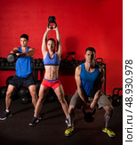 Kettlebell swing workout training group at gym with red wall. Стоковое фото, агентство Ingram Publishing / Фотобанк Лори