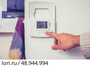 Hand touching thermostat. Стоковое фото, агентство Ingram Publishing / Фотобанк Лори