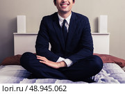 Young businessman sitting on a bed in hotel room. Стоковое фото, агентство Ingram Publishing / Фотобанк Лори