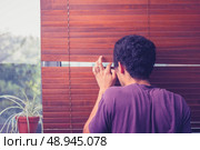 Nosy man peeping out through his blinds and spying on neighbours . Стоковое фото, агентство Ingram Publishing / Фотобанк Лори