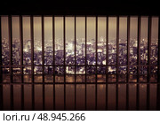 Night city behind the metal grating. Стоковое фото, агентство Ingram Publishing / Фотобанк Лори