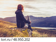 Young woman sitting in the mountains at sunrise. Стоковое фото, агентство Ingram Publishing / Фотобанк Лори