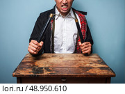 Angry man at table with nunchucks . Стоковое фото, агентство Ingram Publishing / Фотобанк Лори