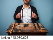 Dangerous man at table with a gun and other weapons. Стоковое фото, агентство Ingram Publishing / Фотобанк Лори