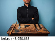 Dangerous man at table with a gun and other weapons. Стоковое фото, агентство Ingram Publishing / Фотобанк Лори
